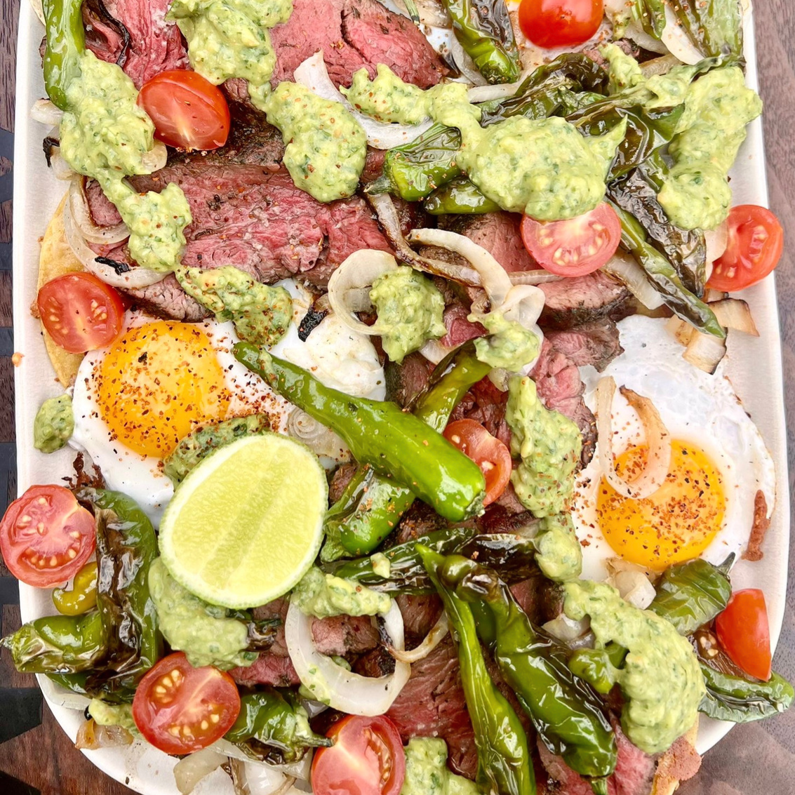 carne asada with blistered shishito peppers, fried eggs, grilled onions and guac sauce