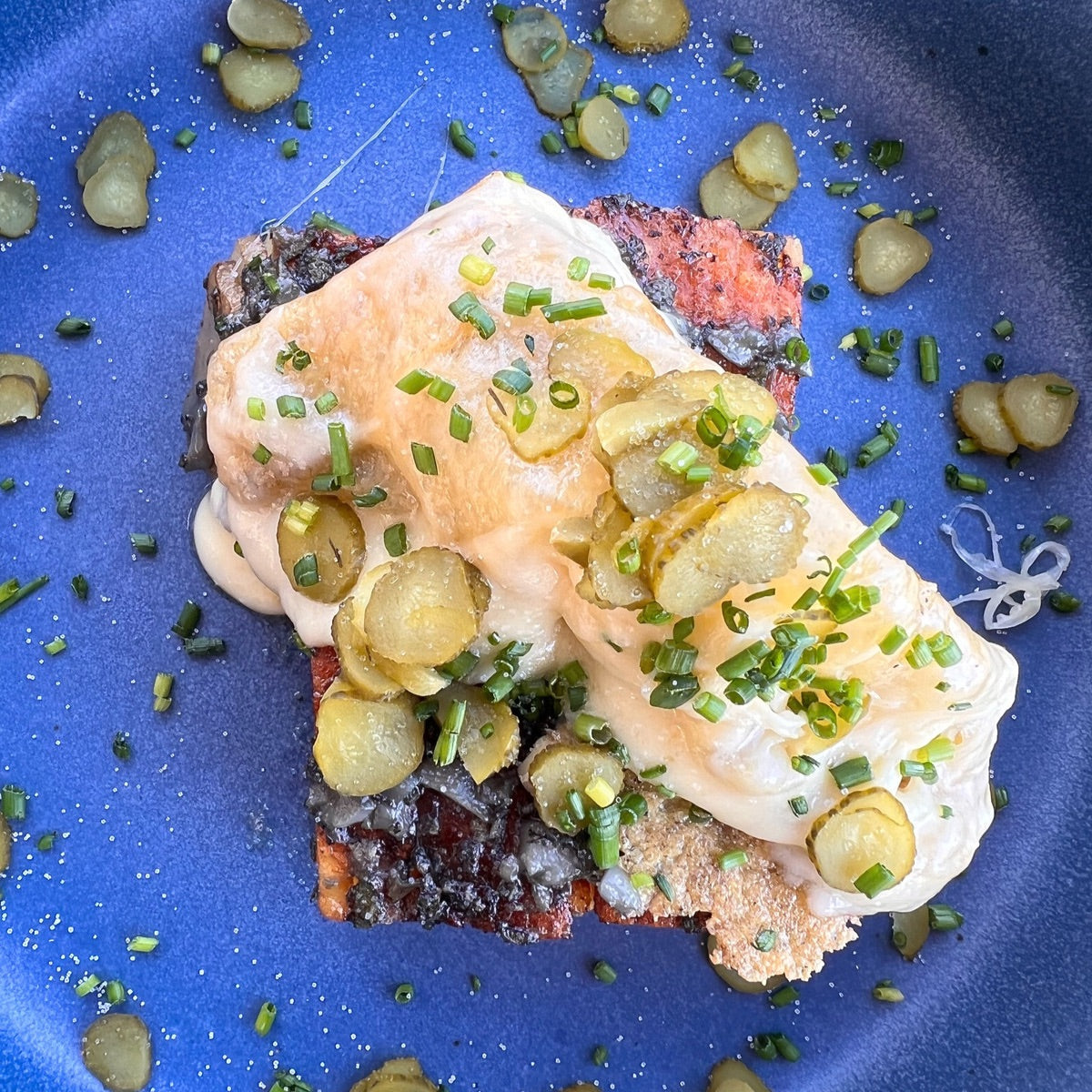 Potatoes dominoes with melted raclette cheese, gherkin pickles and chopped chives