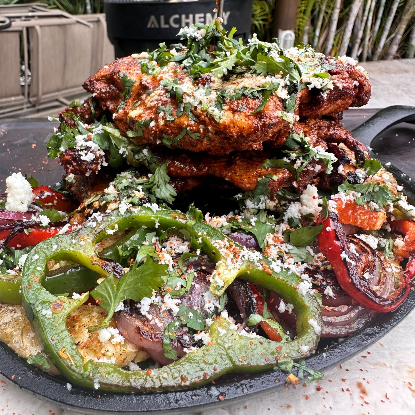 a skillet with grilled peppers, onions and pineapple with smoked fajita chicken stacked on the skillet