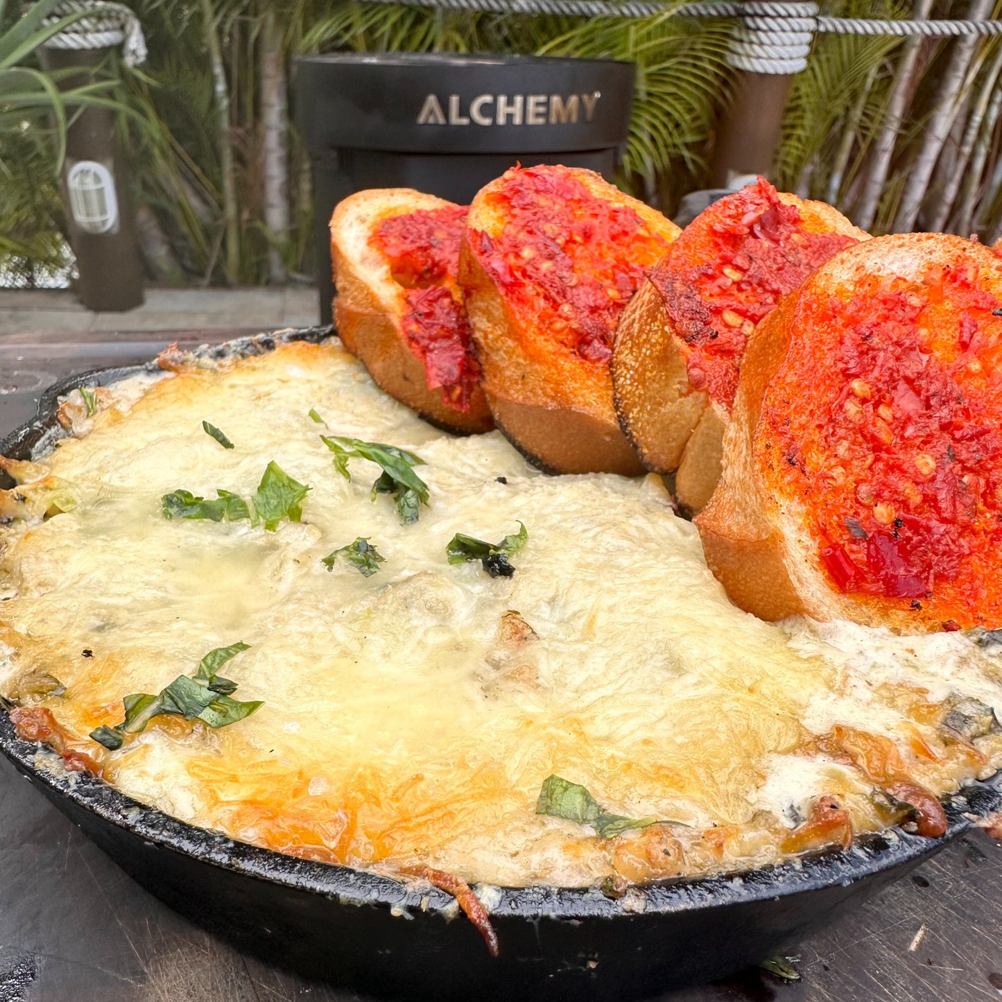 a skillet filled with hot smoked chicken Alfredo dip and baguette with bomba butter