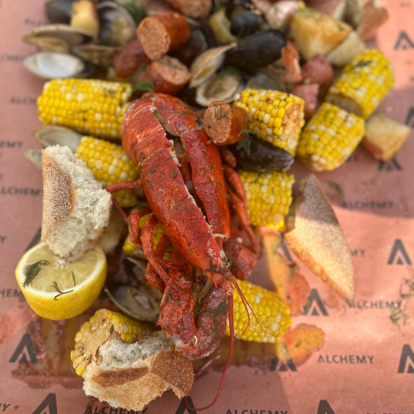 a seafood boil with lobster, clams, mussels, shrimp, corn and potatoes poured out onto parchment paper on a table