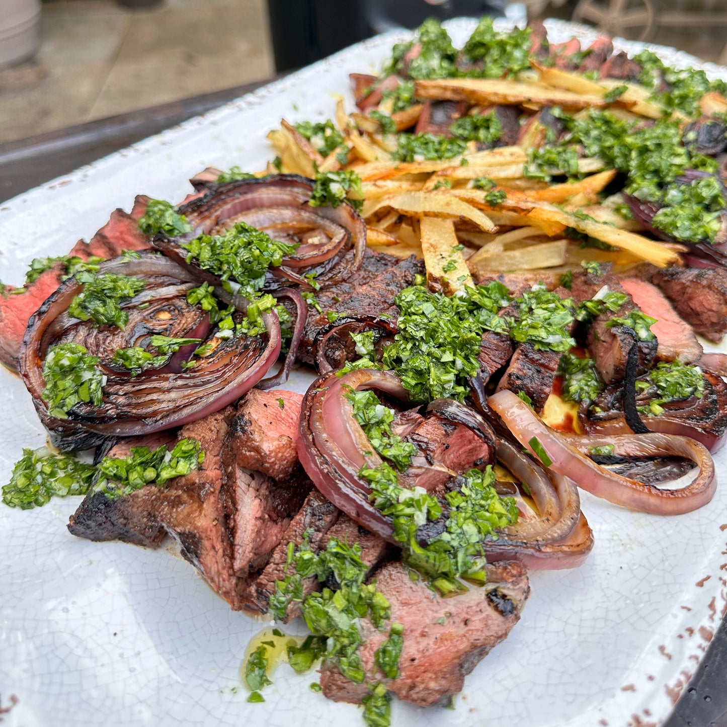 a steak frites platter with grilled onions and chimichurri