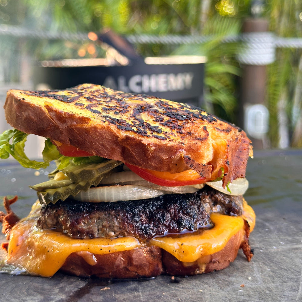 a patty melt with pickles, grilled onions, tomato and lettuce
