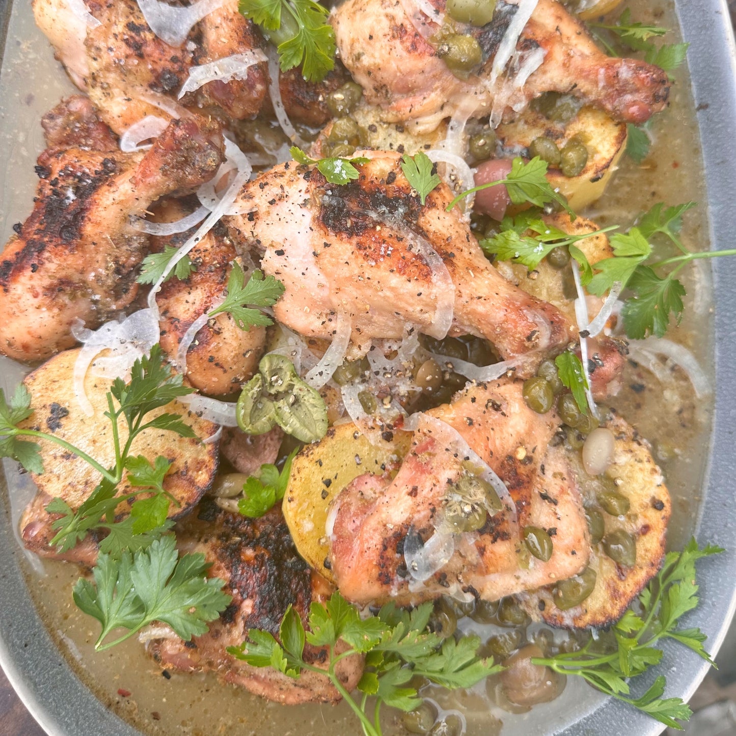 a platter of butterflied smoked chicken drumsticks and greek lemon butter potatoes
